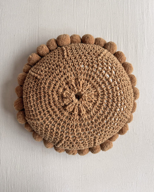 Back of a Camel-colored round wool cushion with visible woolen cords.