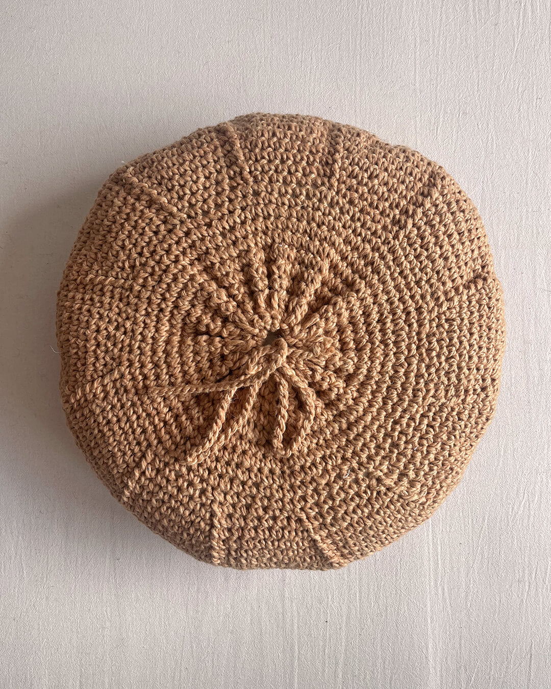 Back of a Camel round cushion made of handwoven wool, with visible woolen tie closure.