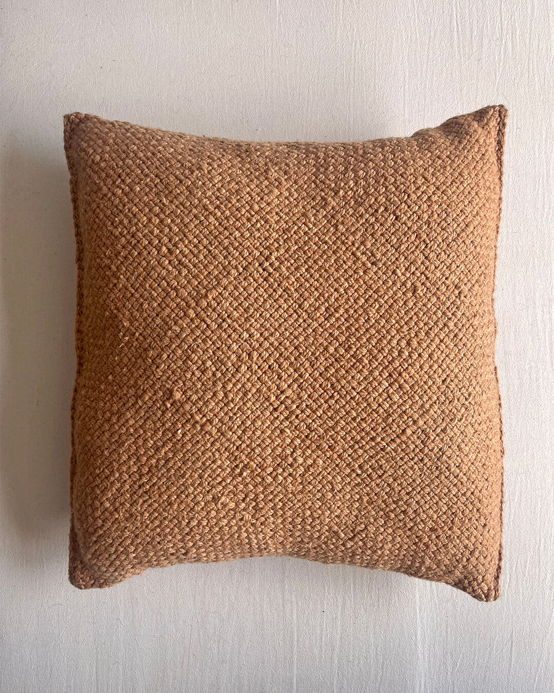 Camel-colored square wool cushion, shown from the front.