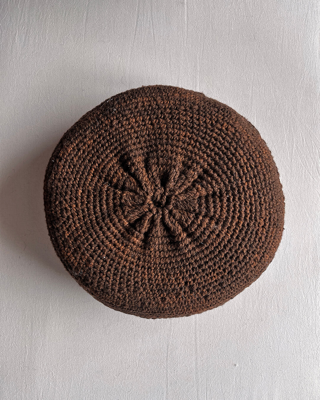 Round cushion in Chocolate Brown and Natural White, shown from the back.