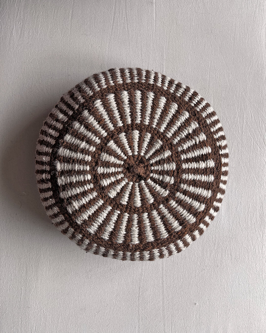 Round cushion in Chocolate Brown and Natural White with comb-pattern design, shown from the front.