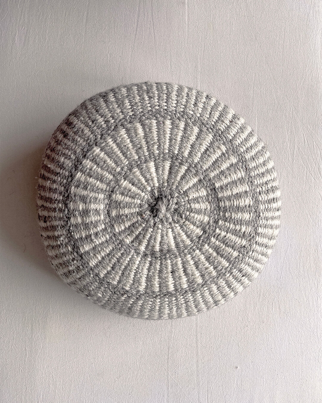 Round cushion in Gray and Natural White with comb-pattern design, shown from the front.