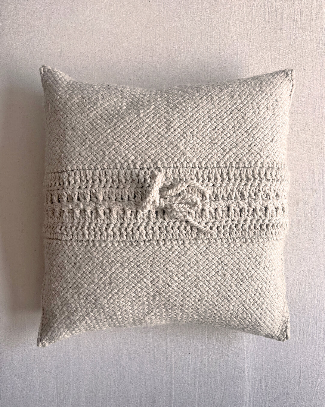 Natural white square wool cushion, shown from the back with woolen tie closure.