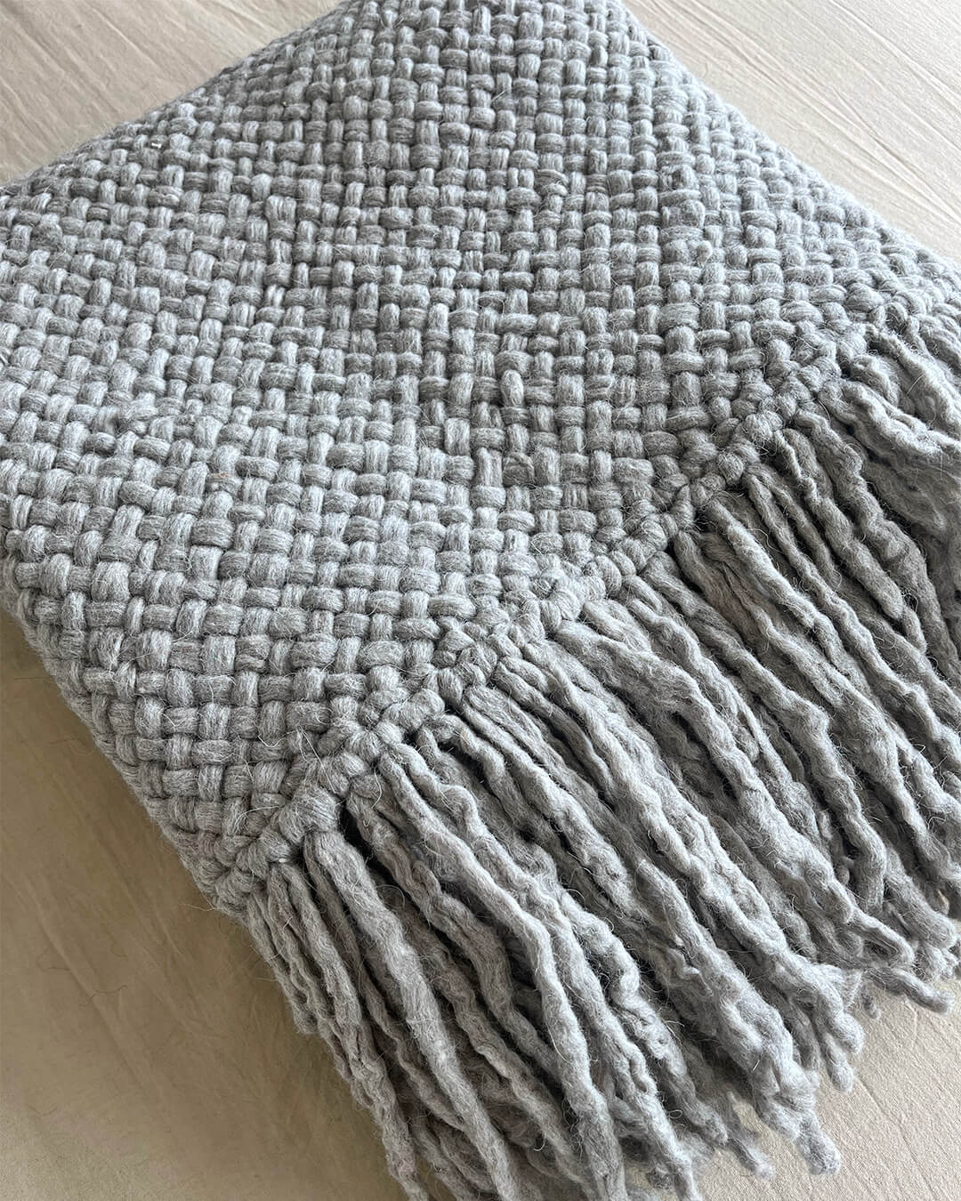 Gray wool throw partially folded to highlight the fringe and texture.