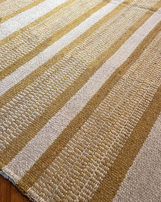 Close-up of a handwoven wool rug featuring natural and onion yellow stripes, highlighting the textured weave and fiber detail.
