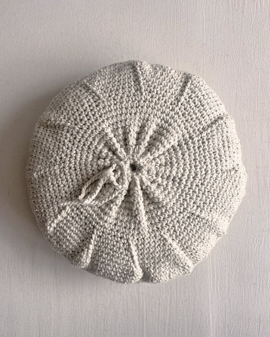 Back of a Natural White round cushion made of undyed handwoven wool, with visible woolen tie closure.