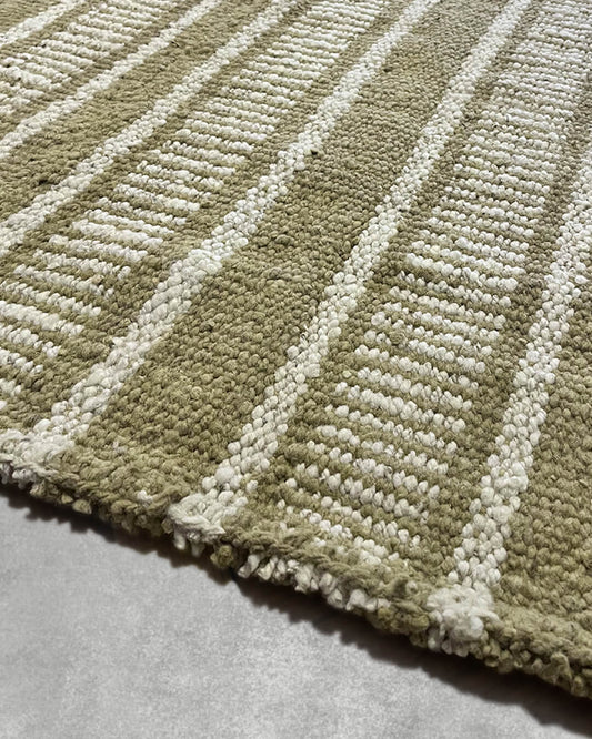 Detail of a handwoven wool rug showing alternating yerba green and natural stripes with textured comb weave.