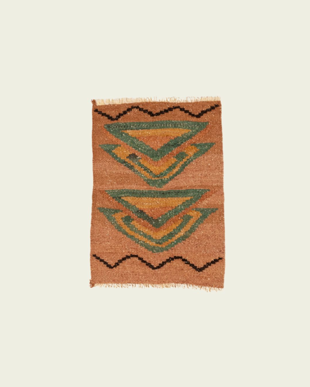 Handwoven Qom mini rug with geometric motifs in terracotta, green, and ochre, finished with short fringes.