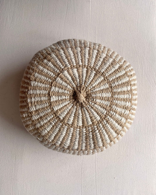 Round cushion in Beige-Sand and Natural White with comb-pattern design, shown from the front.