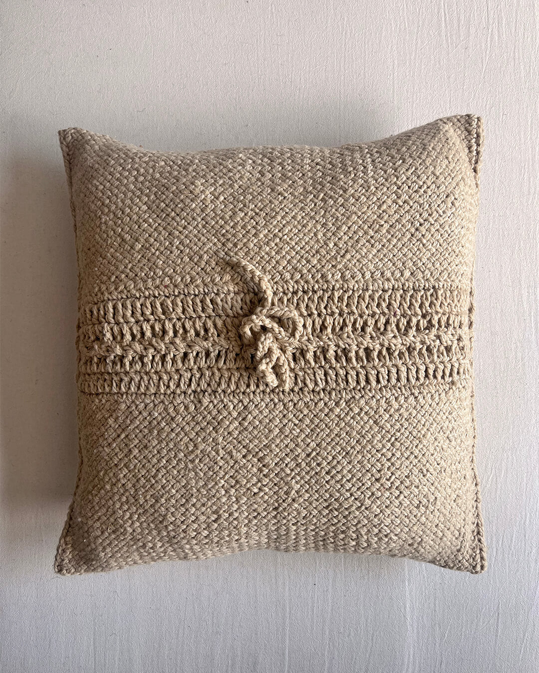 Beige-Sand square wool cushion, shown from the back with woolen tie closure.