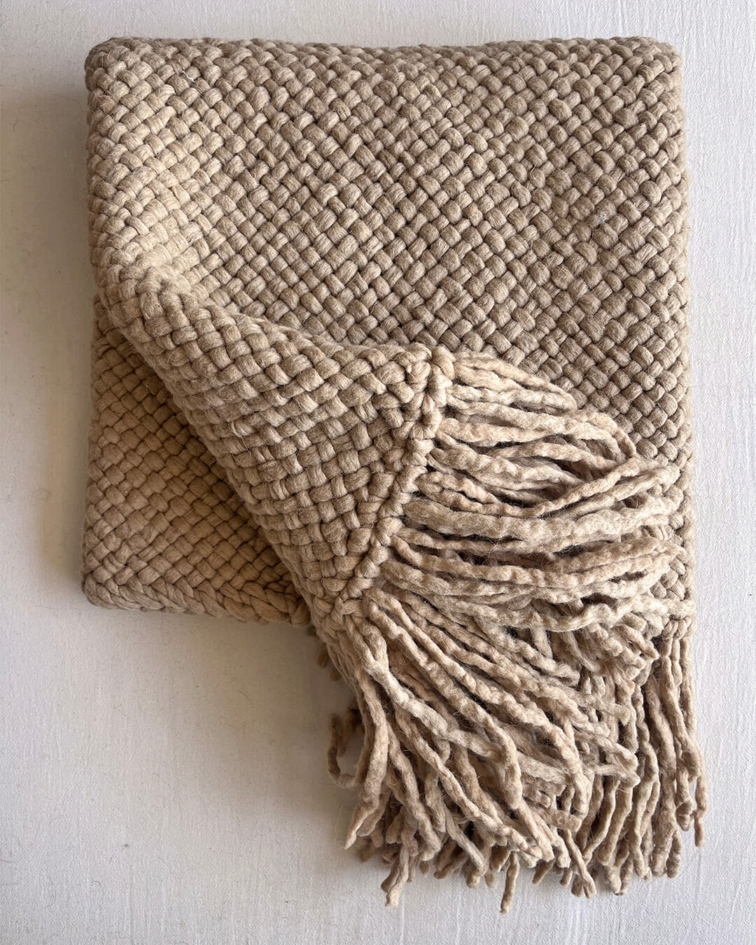 Beige-Sand wool throw partially unfolded to reveal weave and fringes.