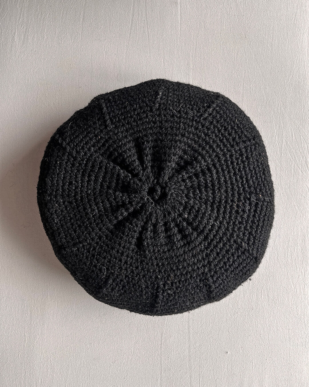 Round cushion in Black and Natural White, shown from the back.