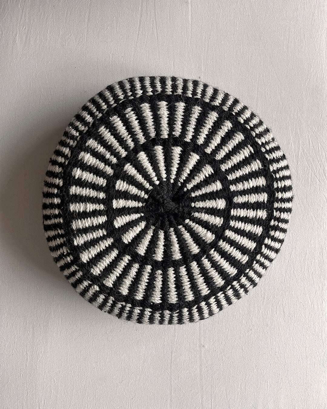 Round cushion in Black and Natural White with comb-pattern design, shown from the front.
