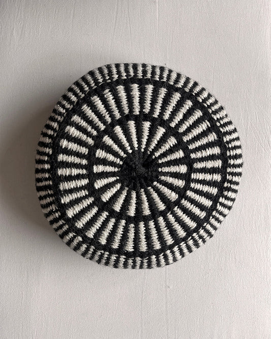 Round cushion in Black and Natural White with comb-pattern design, shown from the front.