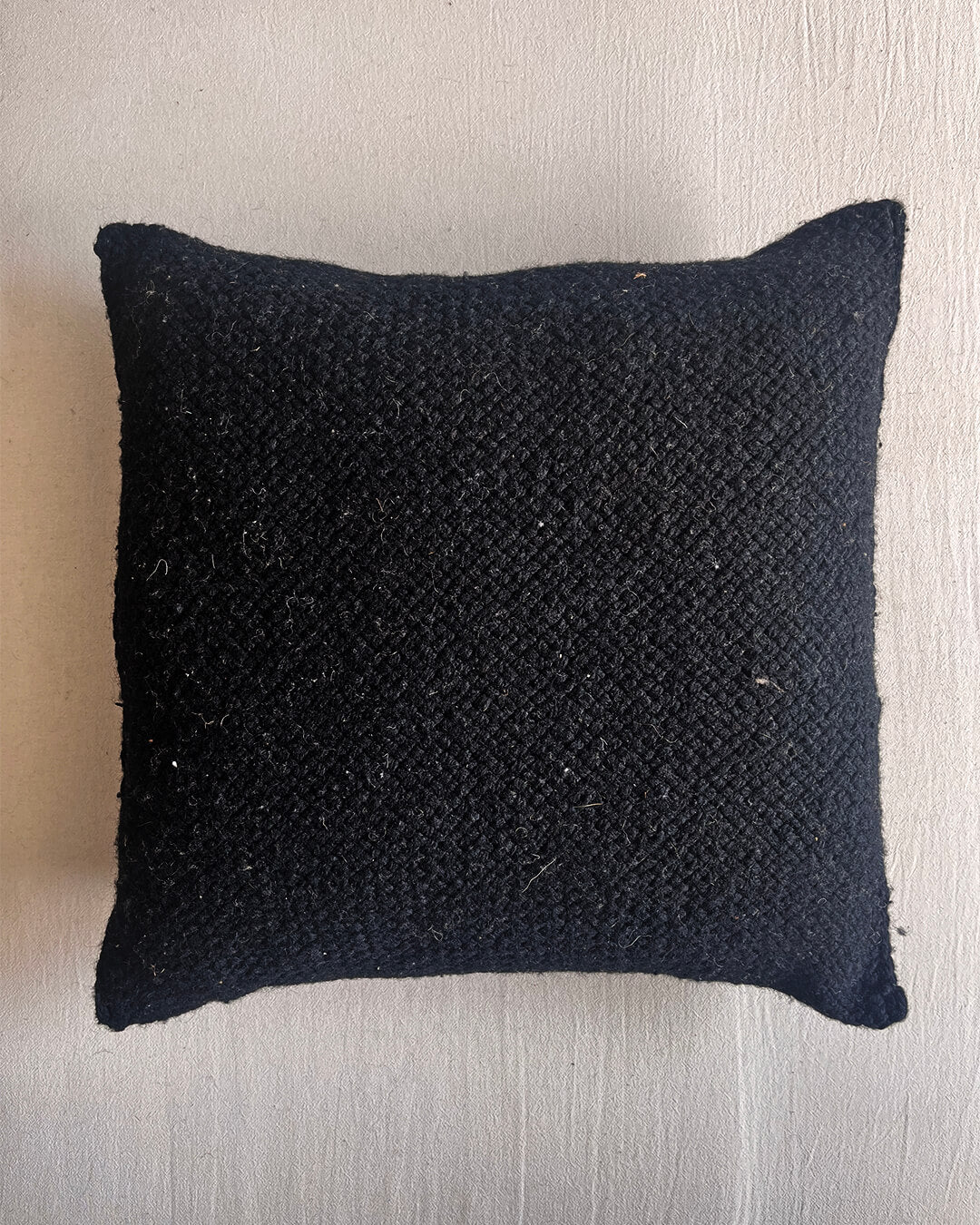 Black square wool cushion, shown from the front.