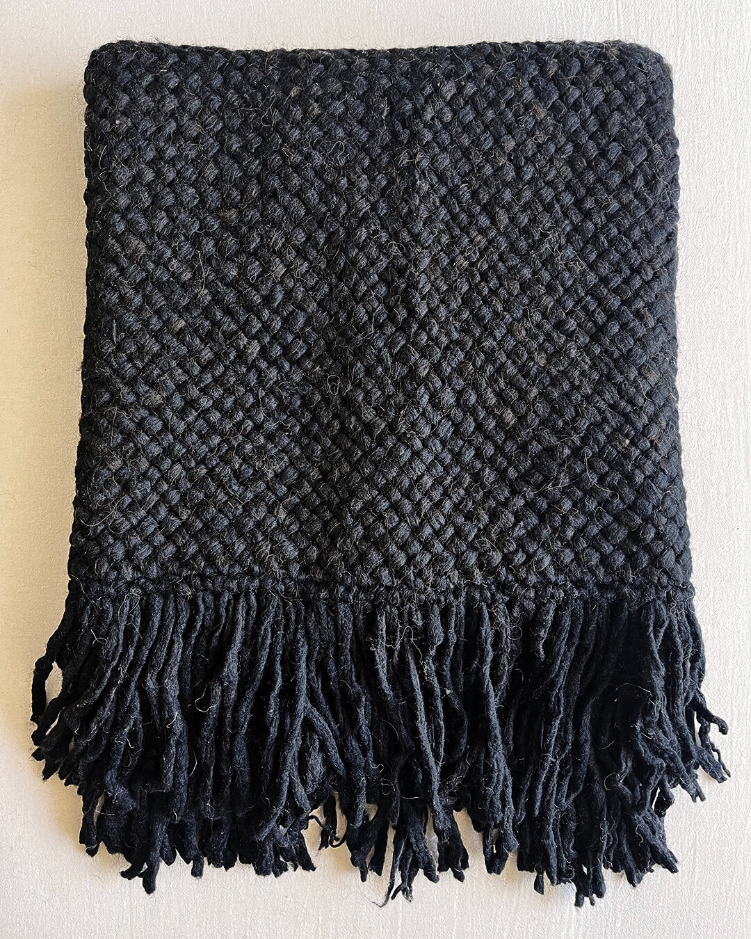 Folded Black wool throw with fringes, presented front-facing on a light background.