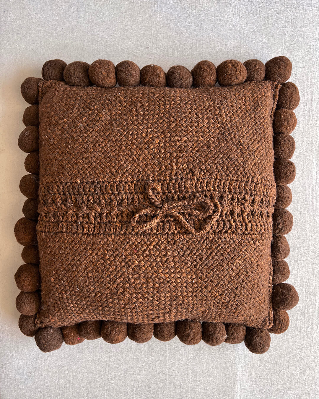 Chocolate Brown square cushion with handmade pom poms, shown from the back.