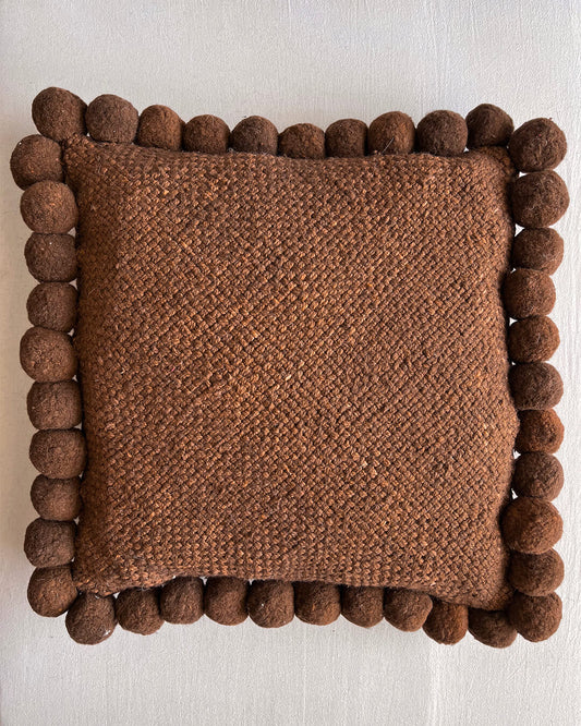 Chocolate Brown square cushion with handmade pom poms, shown from the front.
