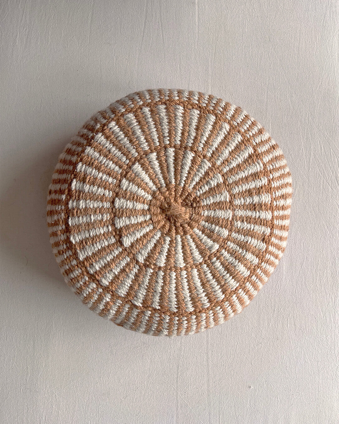 Round cushion in Camel and Natural White with comb-pattern design, shown from the front.