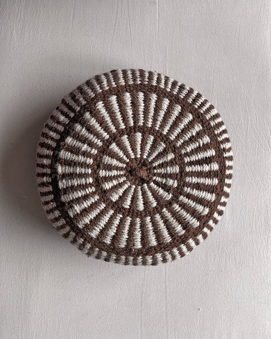 Round cushion in Chocolate Brown and Natural White with comb-pattern design, shown from the front.