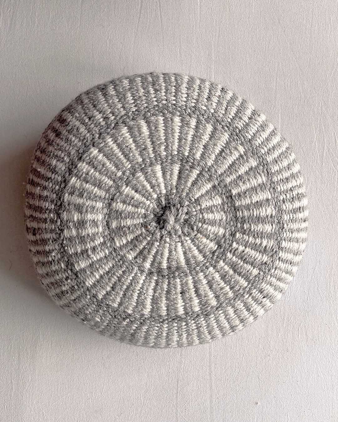 Round cushion in Gray and Natural White with comb-pattern design, shown from the front.