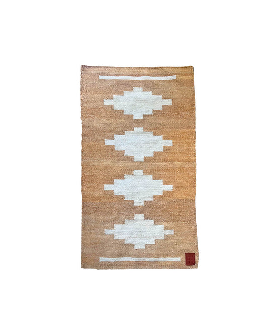 Handwoven CHACO Mini Rug in natural llama fiber with white geometric figures on a warm brown background.