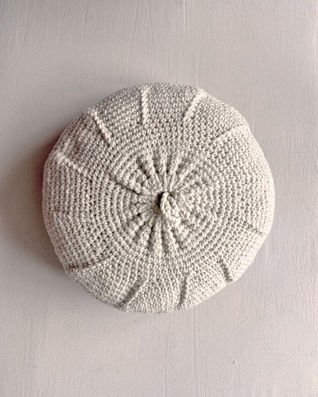 Round cushion in Natural White and Black, shown from the back.