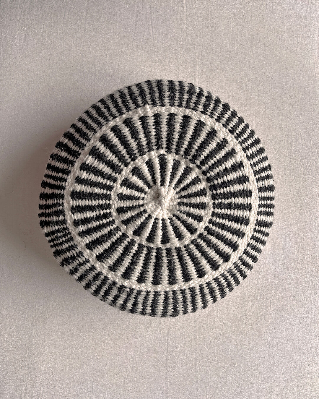 Round cushion in Natural White and Black with comb-pattern design, shown from the front.
