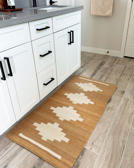 Handwoven CHACO Mini Rug placed in a bright kitchen, featuring a natural brown base with white geometric design.