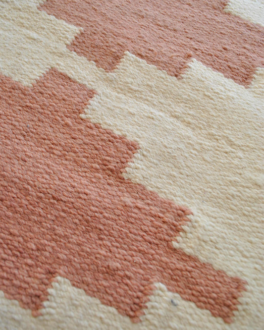 Close-up of the CHACO Mini Rug featuring a geometric pattern in terracotta tones on a natural wool background.