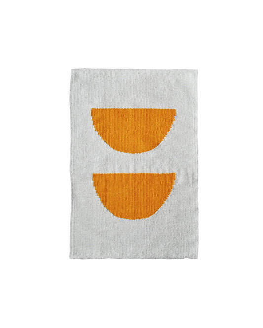Handwoven CHACO Mini Rug with two orange semicircles on a white wool background.