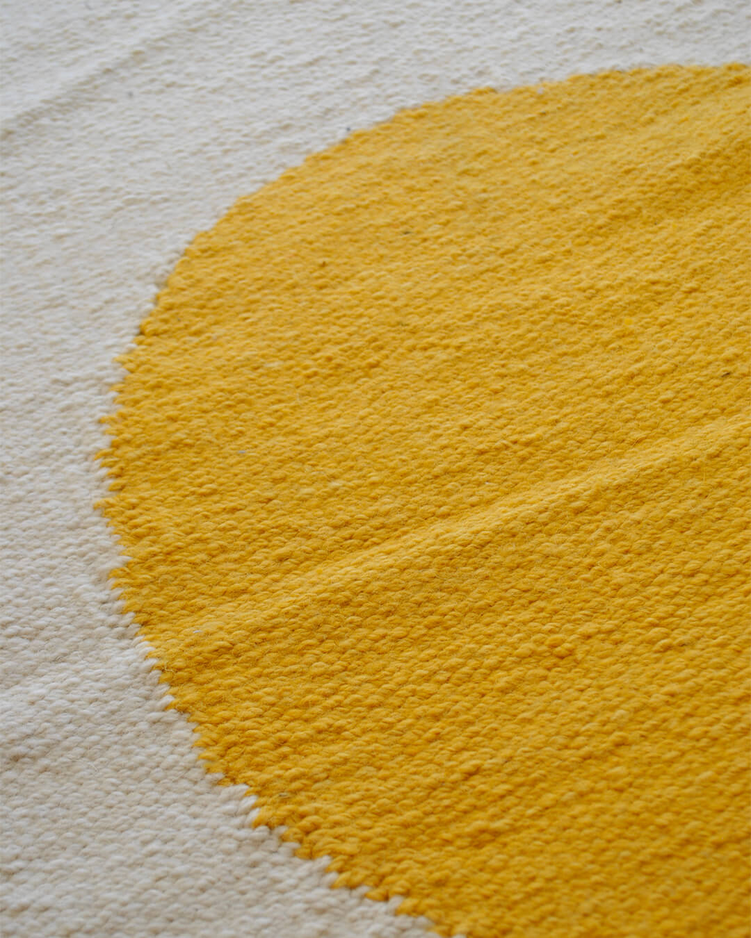Close-up of CHACO’s Mini Rug with a yellow sun pattern handwoven in wool.