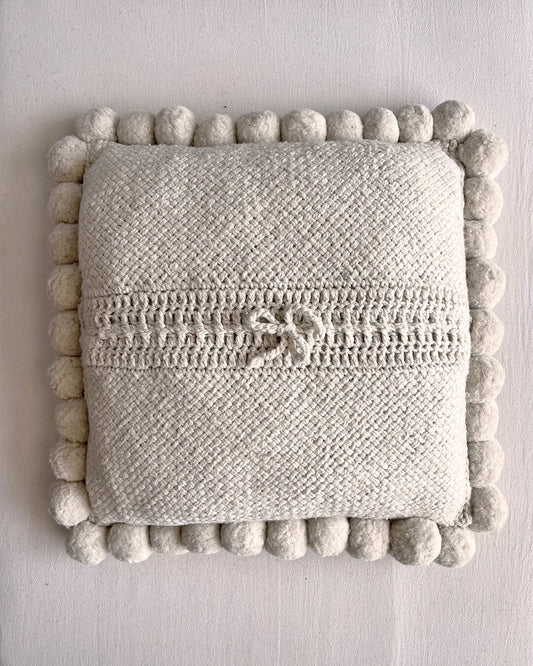 Natural White square cushion with handmade pom poms, shown from the back.