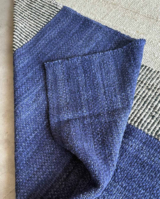 Detail view of a handwoven rug with folded midnight blue wool revealing the thickness and softness of the weave.