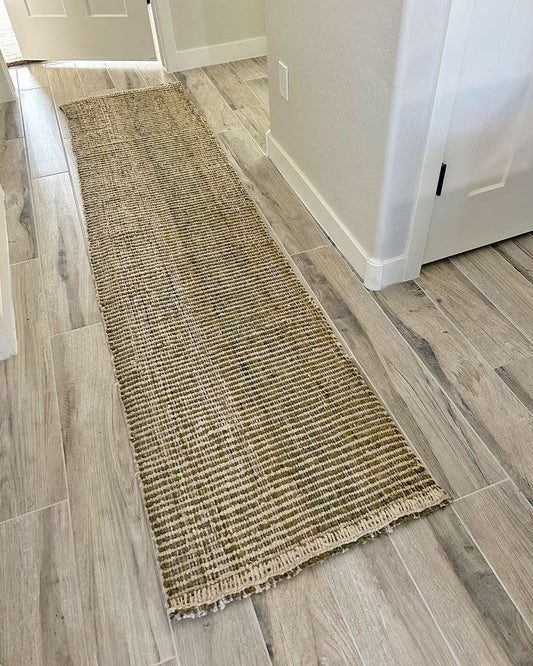 Handwoven runner rug in yerba and natural tones photographed in a hallway, showing its full length, stripe rhythm, and texture.
